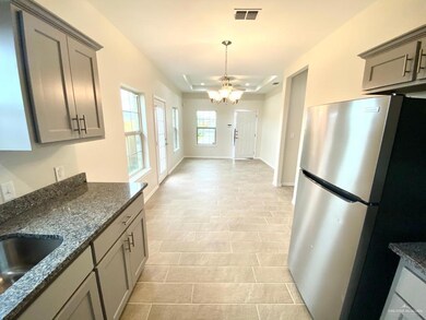Kitchen featuring gray cabinetry, freestanding refrigerator, dark stone countertops, and a chandelier