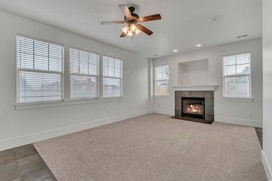 Unfurnished living room featuring a fireplace, a ceiling fan, recessed lighting, and light colored carpet