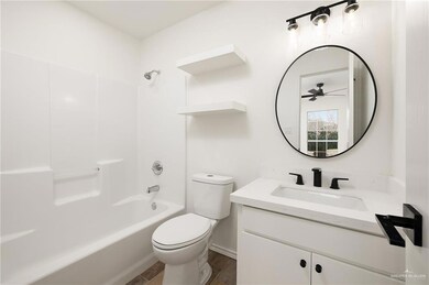 Full bathroom with washtub / shower combination, vanity, toilet, and wood-type flooring