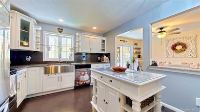 Kitchen with open shelves, tasteful backsplash, glass insert cabinets, white cabinetry, and recessed lighting