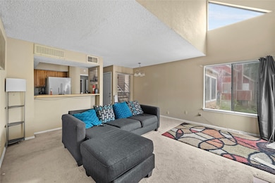 Living room featuring light carpet, a chandelier, and a textured ceiling