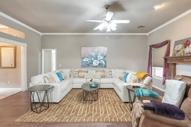 Living room with ceiling fan, crown molding, and w