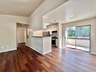 Kitchen with white cabinets, appliances with stainless steel finishes, a textured ceiling, dark wood-style floors, and dark countertops