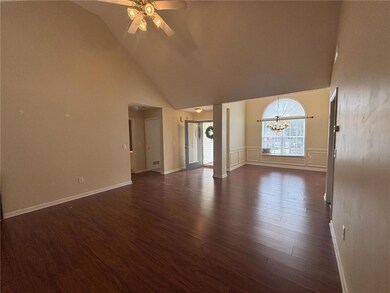 Unfurnished living room with ceiling fan, high vaulted ceiling, dark wood-style floors, a chandelier, and baseboards