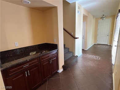 Hall with stairs, baseboards, and dark tile patter