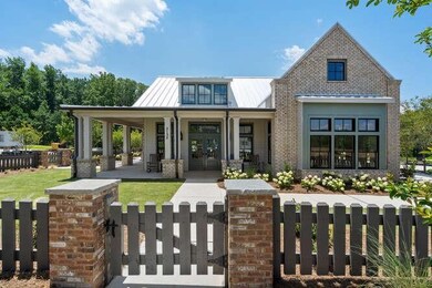 View of front of house featuring metal roof, covered porch, a fenced front yard, a front lawn, and a gate