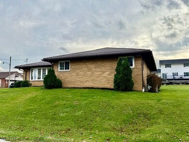 Back of property featuring a lawn, brick siding, and a deck