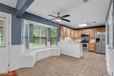 Kitchen featuring light countertops, appliances with stainless steel finishes, a textured ceiling, ceiling fan, and a peninsula