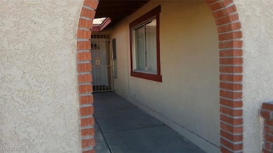 View of exterior entry with stucco siding & security gate