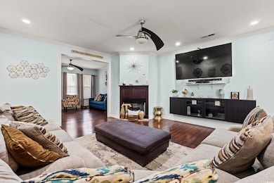 Living room with a ceiling fan, ornamental molding, wood finished floors, recessed lighting, and a fireplace