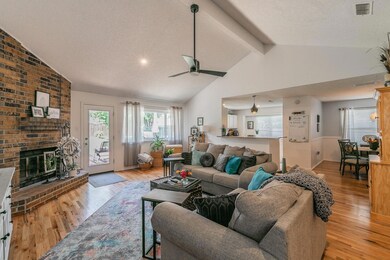 Living room featuring light hardwood / wood-style flooring, a fireplace, and lofted ceiling with beams