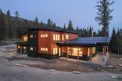 View of front facade featuring a standing seam roof, a wooded view, and a metal roof