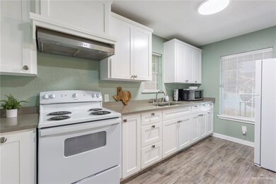 Kitchen featuring white cabinetry, light hardwood / wood-style flooring, white appliances, ventilation hood, and sink