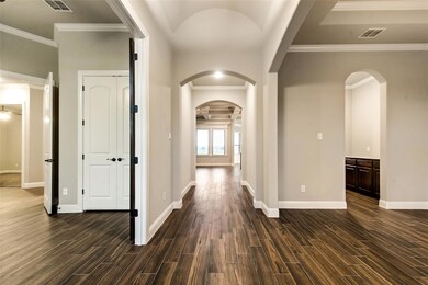 Hall featuring dark wood-style floors, visible vents, arched walkways, and baseboards