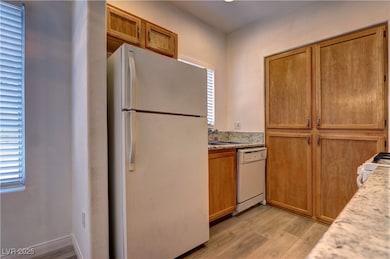 Kitchen featuring white appliances, light wood fin