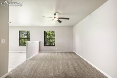 Carpeted spare room with ceiling fan and baseboards