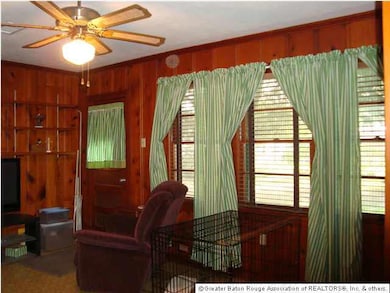 The Den has rich paneled walls, ceiling fan, a wal