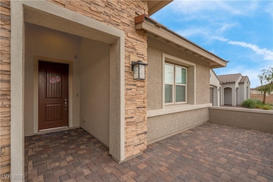 View of exterior entry with stucco siding and ston