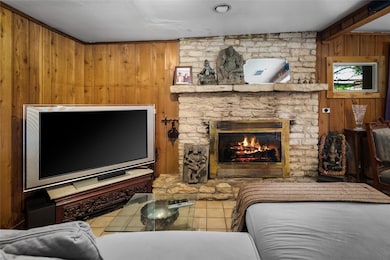 Tiled living area with wooden walls and a stone fireplace