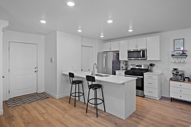 Kitchen with a breakfast bar, a peninsula, appliances with stainless steel finishes, white cabinetry, and recessed lighting