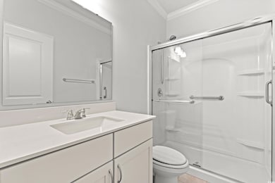 Full bath featuring a shower stall, ornamental molding, and vanity