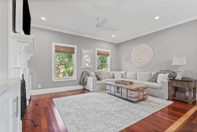 Living room with crown molding, dark wood-style floors, recessed lighting, and gas fireplace.