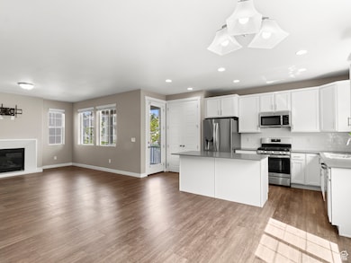 Kitchen with open floor plan, appliances with stainless steel finishes, decorative backsplash, white cabinets, and recessed lighting