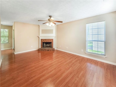 Unfurnished living room with a ceiling fan, light wood-style floors, baseboards, and a brick fireplace