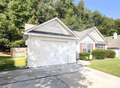 Single story home featuring driveway, a front yard, and an attached garage