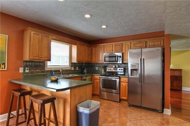 Kitchen features stainless appliances and tiled floor.