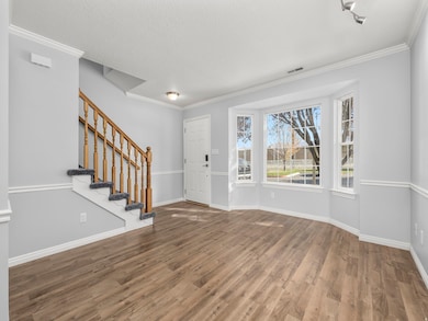 Entrance foyer featuring ornamental molding, stairway, wood finished floors, and a textured ceiling