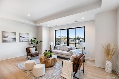 Living area featuring recessed lighting, light wood-style flooring, and a raised ceiling