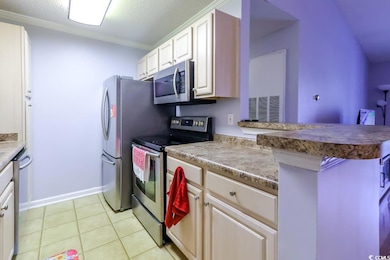 Kitchen with appliances with stainless steel finishes, ornamental molding, light tile patterned flooring, baseboards, and a peninsula