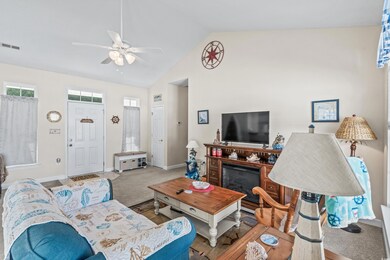 Carpeted living room with ceiling fan and high vau