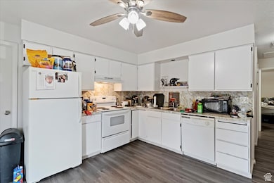 Unit 1 Kitchen featuring white appliances, white cabinetry, light countertops, dark wood finished floors, and tasteful backsplash