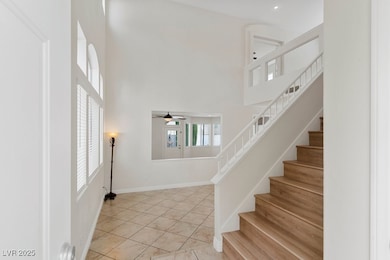 Stairway with tile patterned floors, a towering ceiling, a ceiling fan, and recessed lighting