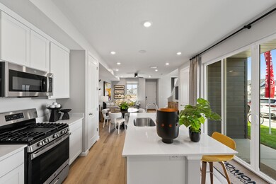 Kitchen featuring stainless steel appliances, open floor plan, a center island with sink, light wood finished floors, and recessed lighting