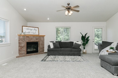 Living room featuring healthy amount of natural light, carpet floors, a ceiling fan, a fireplace, and recessed lighting
