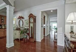 Corridor featuring dark wood-type flooring, ornate columns, and ornamental molding