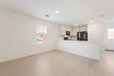 Kitchen with light wood-style flooring, visible vents, baseboards, light countertops, and black appliances
