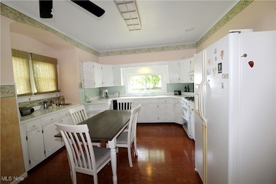 Kitchen with white fridge with ice dispenser, range with two ovens, dark wood-type flooring, white cabinets, and light countertops