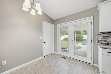 Doorway with french doors, vaulted ceiling, and a chandelier