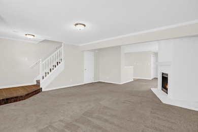 Unfurnished living room with crown molding, carpet, stairs, and a fireplace