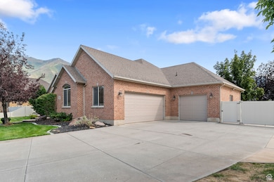 View of side of property with a shingled roof, brick siding, driveway, a garage, and a gate