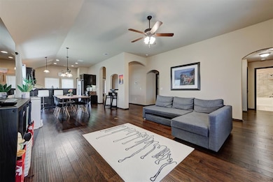 Living room featuring arched walkways, a ceiling fan, lofted ceiling, dark wood-type flooring, and recessed lighting