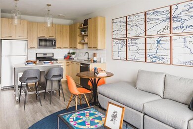 Kitchen with tasteful backsplash, hanging light fixtures, light brown cabinets, appliances with stainless steel finishes, and light hardwood / wood-style flooring