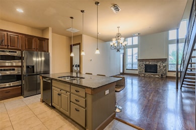 Kitchen with a kitchen bar, a fireplace, hanging light fixtures, dark stone counters, and stainless steel appliances