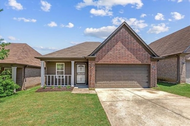 View of front of property featuring brick siding, an attached garage, driveway, and a front yard