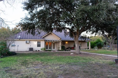 Ranch-style home featuring a standing seam roof, a metal roof, a front lawn, covered porch, and french doors