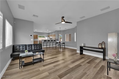 Living room with light wood-style flooring, a ceiling fan, and recessed lighting